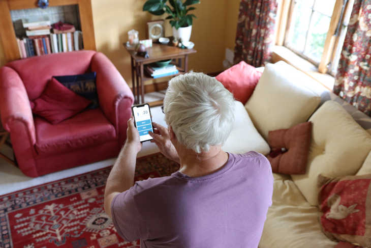 An older man looks at the Nymbl app on his phone. 