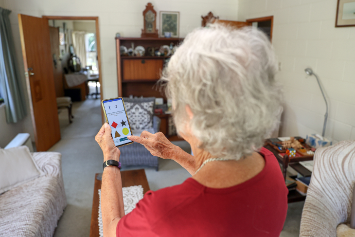 An older woman looks at the Nymbl app on her phone.