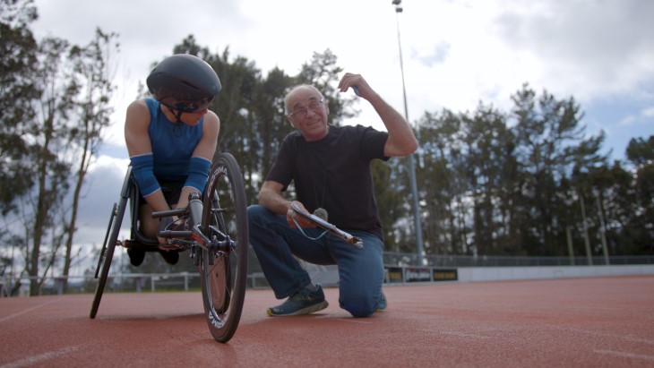 A Para sport coach talking to an athlete on a running track. 