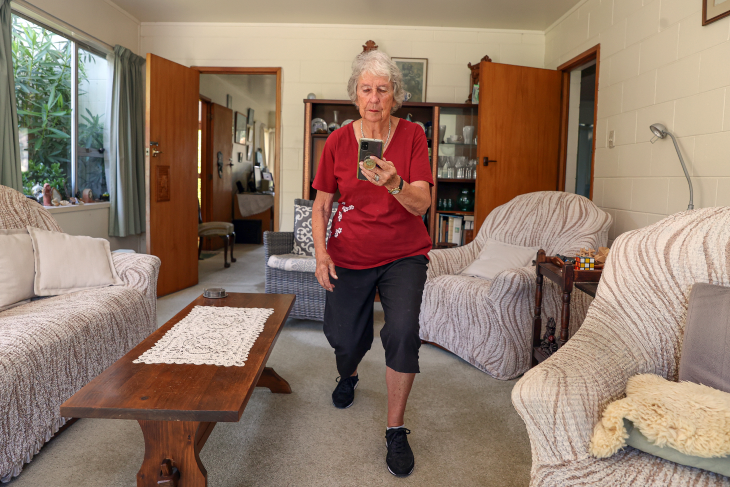 Penny Wilson using the Nymbl app by looking at her phone and doing an exercise in her living room. 
