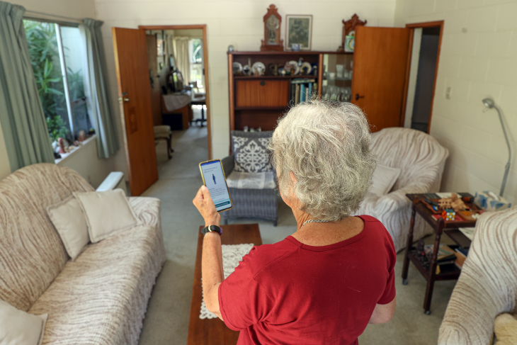 Penny Wilson shown from behind looking at her phone to use the Nymbl app. 