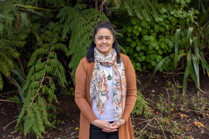 A portrait photo of Pollyanne Taare smiling in front of a background of native bush.