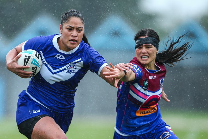 A female rugby league player running with the ball while an opponent tries to tackle her.