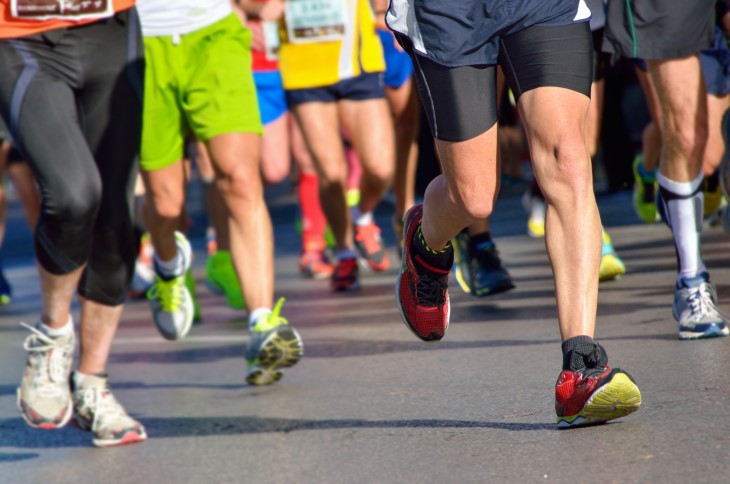 A close-up photo showing the legs of people who are all competing in a long-distance running event.