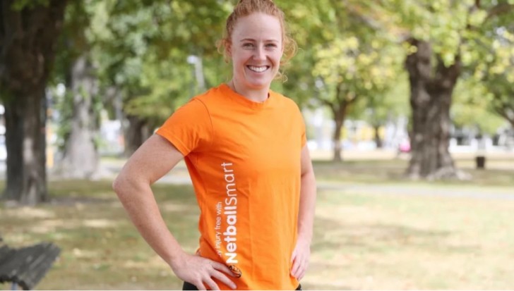 Sam Winders wearing an orange NetballSmart t-shirt and smiling.
