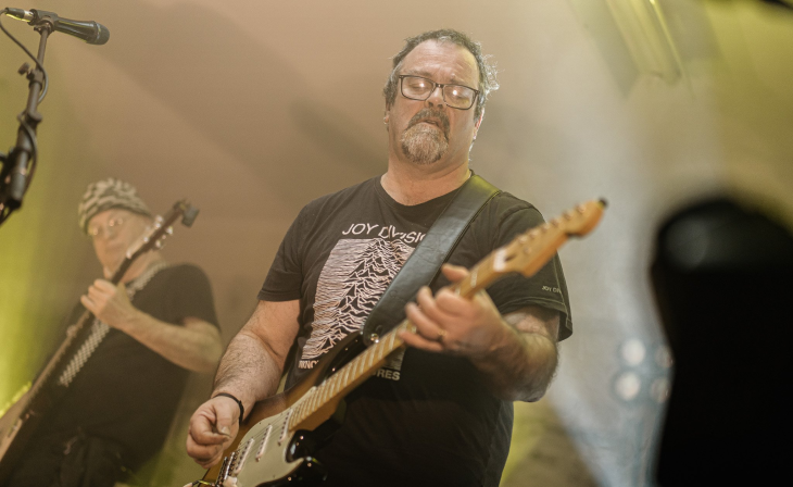 Simon Gotlieb on stage playing an electric guitar in a band.