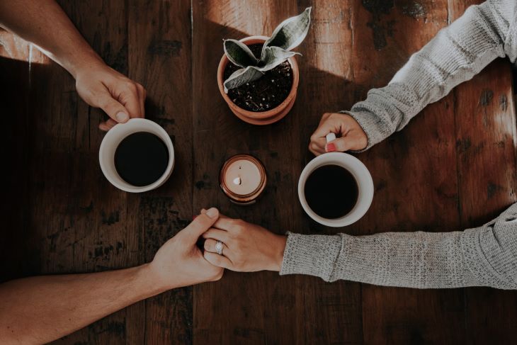 Two people hold hands over coffee