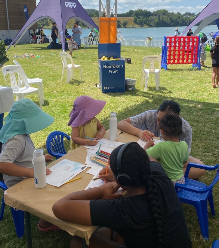 Several children sitting down at a table and drawing in the ACC Whānau Zone at the Waka Ama Sprint Nationals.