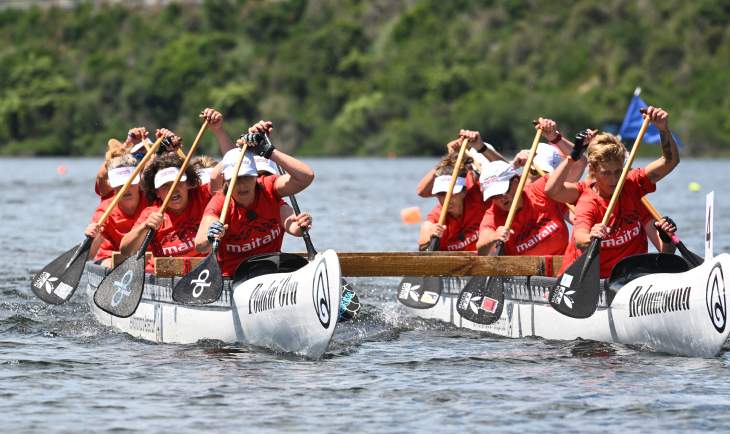 A group of women on an outrigger canoe competing in waka ama. 