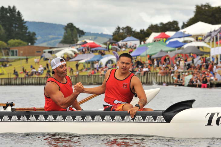 Two men congratulating each other in their outrigger canoe after a waka ama race. 