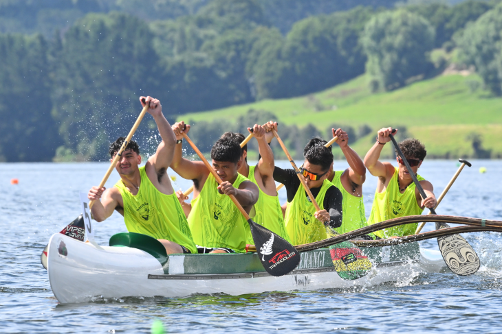 A group of young boys in an outrigger canoe competing in waka ama. 