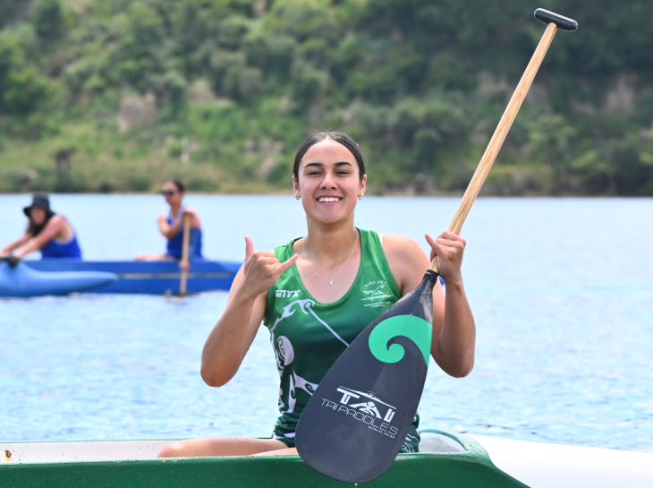 A young woman posing for the camera in her outrigger canoe. 