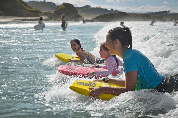 Children boogie-boarding on waves at the beach. 