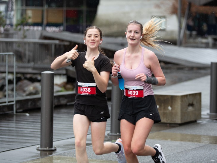 Two females running the Wellington Marathon and smiling for the camera.