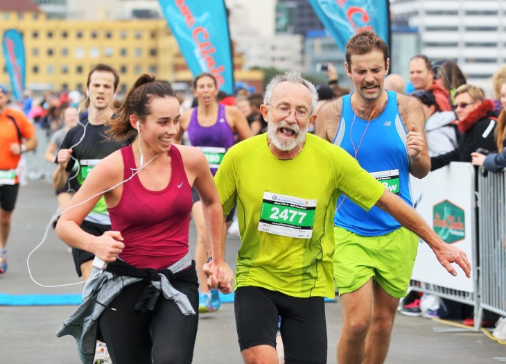 A young woman holding the hand of an older man as they run the Wellington Marathon.